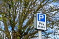 A parking pay here sign on a lamp post