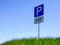 Parking road sign on a background of green grass and blue sky Royalty Free Stock Photo