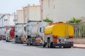 Parking row jam of trucks with fuel tanks in front of a warehouse and storage of huge tanks of raw material containers