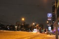 Parking sign neon light at night over dark sky arrow illuminated by lanterns. night street in winter