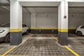 Parking spaces delimited with yellow paint on the ground floor of a building with a garage and parked vehicles Royalty Free Stock Photo