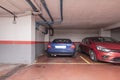 Parking spaces marked out with yellow paint on the ground floor of a garage building with red floors, exposed pipes and parked Royalty Free Stock Photo