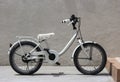 a parking white child bicycle with cement wall as background.