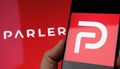 Parler app logo seen on the screen of smartphone and on the blurred background. Parler is a new social media platform promoting