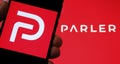Parler app logo seen on the screen of smartphone and on the blurred background. Parler is a new social media platform promoting