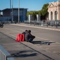 Parma, Italy - November 2020: Boys Delivering Food at Home who is Resting Outdoor Sitting Next to Their Cube-shaped Backpack