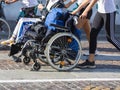 Disabled Athlete in a Sport Wheelchair during Marathon Helped by Female Runners