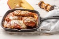 Parmegiana Steak also known as Filet Parmegiana in a black iron pan on a wooden white background, cheese and tomato sauce. Soft Royalty Free Stock Photo