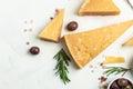 Parmesan cheese on a wooden board, Hard cheese, olives, rosemary and metal grater on a light background. place for text, top view