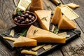 Parmesan cheese on a wooden board, Hard cheese, olives, rosemary and metal grater. place for text, top view