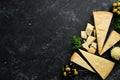 Parmesan. Pieces of Parmesan cheese on black stone background. Top view.