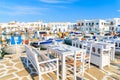 Greek tavern tables and fishing boats anchoring in Naoussa port, Paros island, Greece Royalty Free Stock Photo