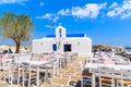 Tavern tables on square with typical white Greek church in Naoussa port, Paros island, Cyclades, Greece Royalty Free Stock Photo