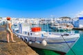 Young woman tourist standing on pier in front of a fishing boat in Naoussa port, Paros island, Greece Royalty Free Stock Photo