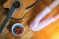 On the parquet floor guitar, a ÃÂup of strawberries, female feet in socks.