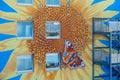 Part of an artistically painted house, skyscraper with a huge sunflower blossom and a peacock butterfly on blue house wall, mural