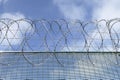 Part of a barbwired fence on a blue sky with clouds