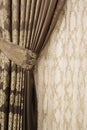 Part of beautifully draped curtain on the window in the room. Close up of piled curtain. Luxury curtain, home decor. Gold and brow