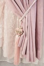 Part of beautifully draped curtain on the window in the room. Floral tassel tieback. Close up of piled curtain. Pink luxury Royalty Free Stock Photo