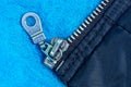Part of black cloth with a gray metal zip on a blue woolen fabric