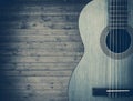 Part of a blue acoustic guitar on a gray wooden background.