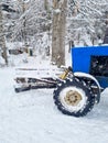 part of a blue tractor with large wheels in a snowy forest. Royalty Free Stock Photo