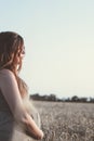 Part of body of beautiful young pregnant woman walks on wheat field at sunset, face profile of expectant mother stroking her belly Royalty Free Stock Photo
