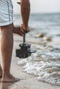 Part of the body of a young man with a camera attached to a steadicam, a videographer shoots video walking barefoot along the