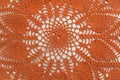 Part of bright orange crocheted product. Openwork napkin for decor on white background. Knitted lace pattern