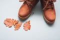 Part of brown autumn pair of boots on gray background with autumn oak leaves with copy space