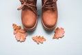 Part of brown autumn pair of boots on gray background with autumn oak leaves with copy space