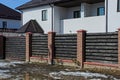 Part brown fence and closed gates of wood on the street near the road