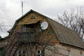 Part of a brown house with a balcony and a satellite antenna overgrown with vegetation Royalty Free Stock Photo