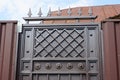 Part of a brown iron door with a wrought pattern