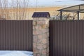 Part of a brown wall of a fence made of stones and metal