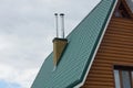 Part of a brown wooden house under a green tiled roof with two metal chimneys Royalty Free Stock Photo