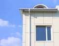 Part of a building wall with window and gutter against the blue cloudy sky Royalty Free Stock Photo