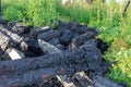 Part of a burnt down wooden house against a background of green grass on a sunny summer day. Selective focus