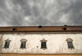 Part of castle Moravsky Krumlov, Czech Republic. Detail of old house with old flaked away facade and dramatic dark clouds above Royalty Free Stock Photo