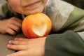 part of a child's face with a beautiful smile and a red apple with a cut out heart