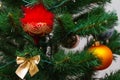 A part of christmas tree with red and orange balls, gold bow on faux Christmas tree. New years card, selective focus Royalty Free Stock Photo