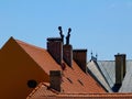 Part of clay tile roof structure and brick chimneys with concrete capping and metal wind vane. Royalty Free Stock Photo