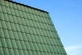 Part of country house roof from green metal tile against blue sky