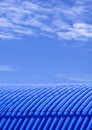 Curve corrugated steel warehouse roof against cloud on blue sky background in vertical frame Royalty Free Stock Photo