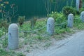 Part of a decorative fence made of gray concrete posts and an iron chain