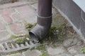 Part of dirty brown gutter pipe on gray wall