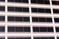 Part of the exterior facade of a modern commercial office building with large rectangular tinted windows Royalty Free Stock Photo