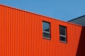 Part of the facade of a red warehouse building with two windows against a blue sky. The concept of renting or selling Royalty Free Stock Photo