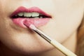 Part of face. Woman applying pink lipstick with brush Royalty Free Stock Photo