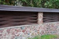 Part fence of brown wooden boards and a stone foundation